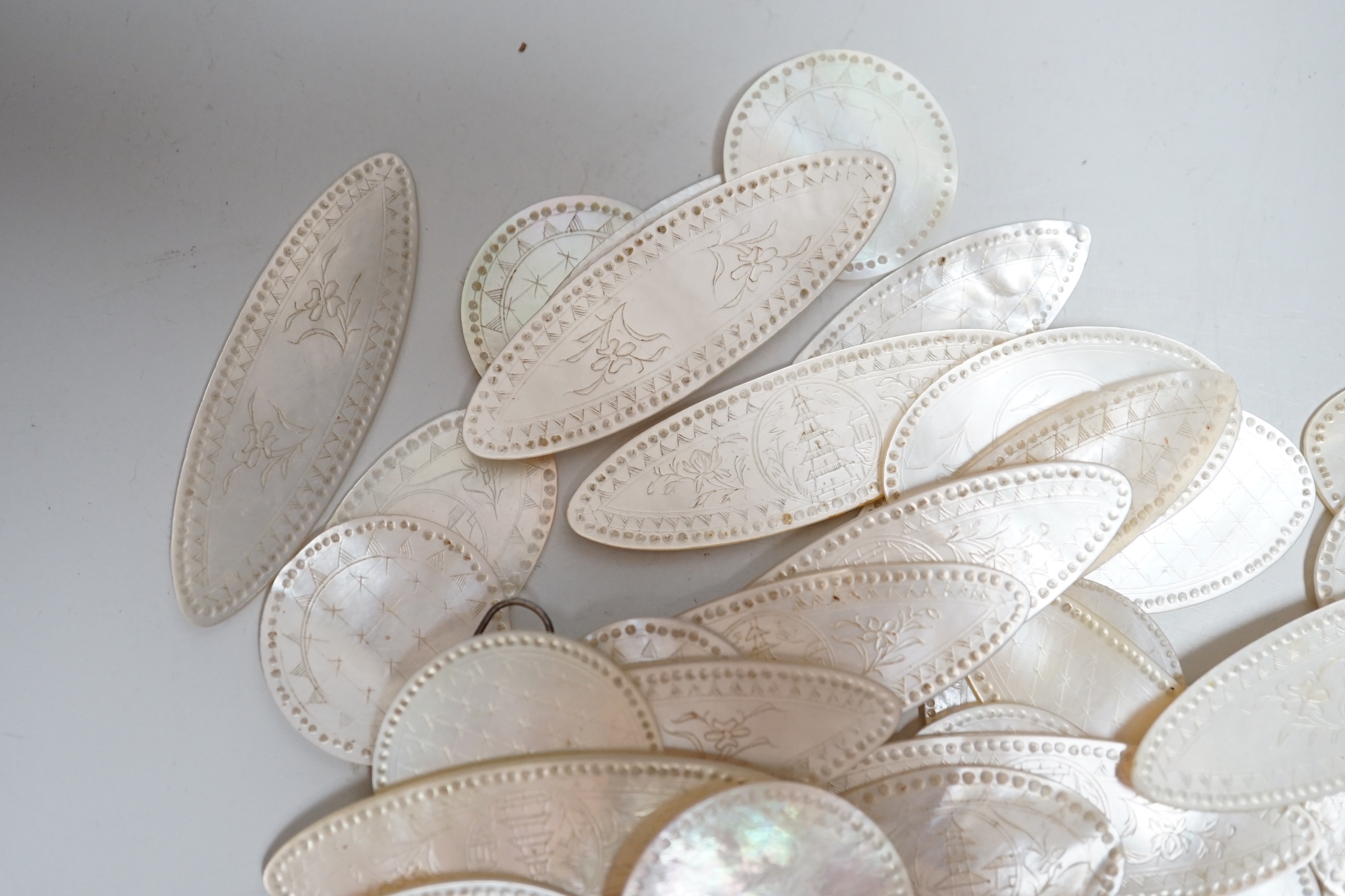 A collection of Chinese mother of pearl counters or tokens including two converted to drop earrings, the largest 5cm wide